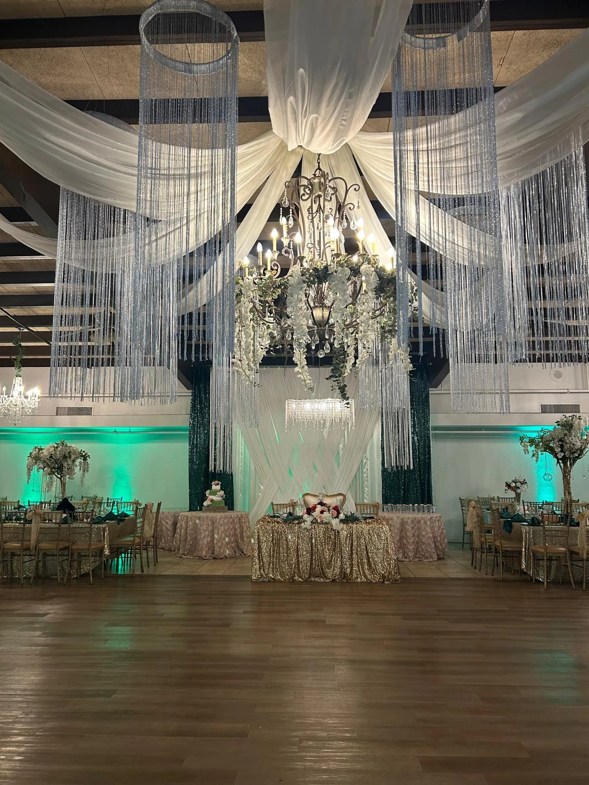 Crystal chandelier, ivory draping and silver hanging strands above the ballroom floor